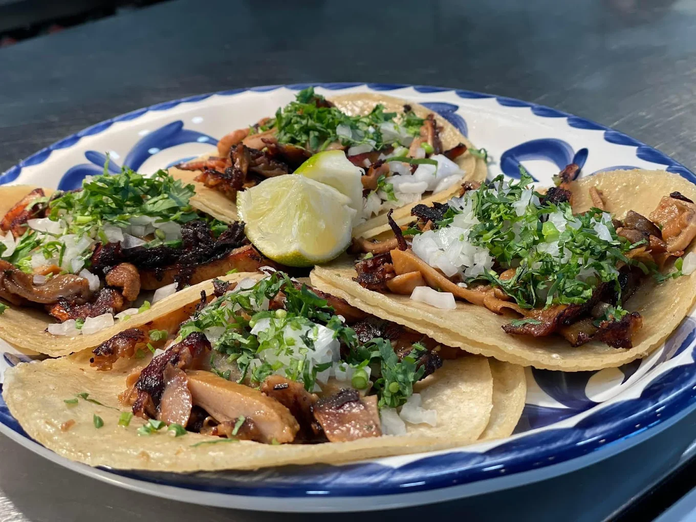 Street tacos with cilantro, onion and lime on a talavera plate